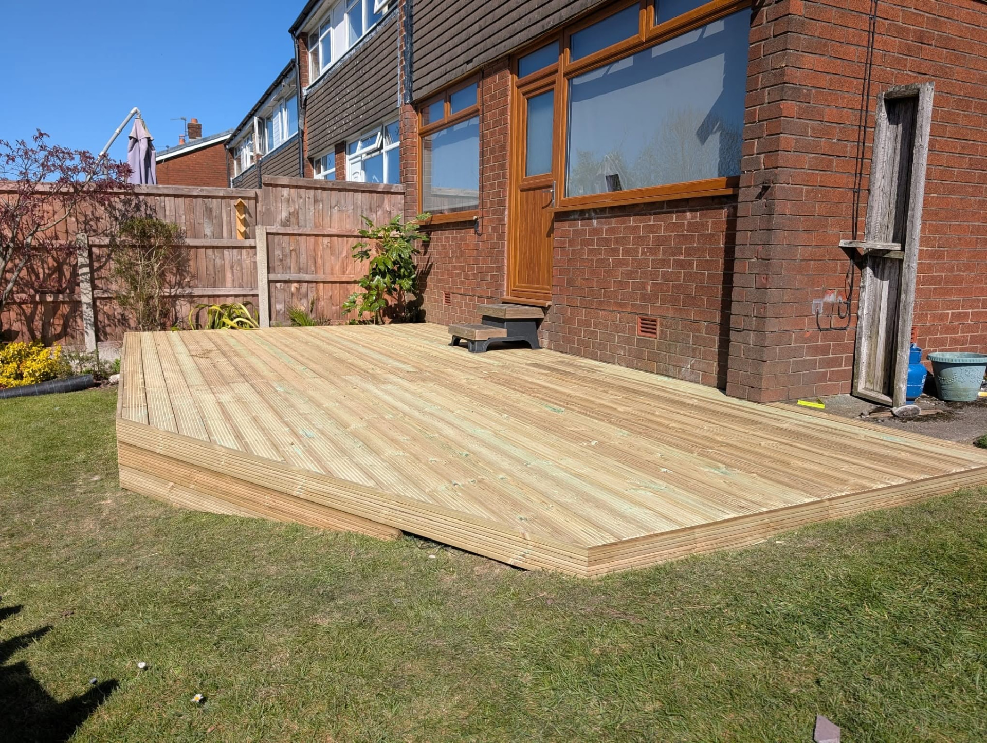 Raised timber decking with chamfered edges built alongside a brick house wall